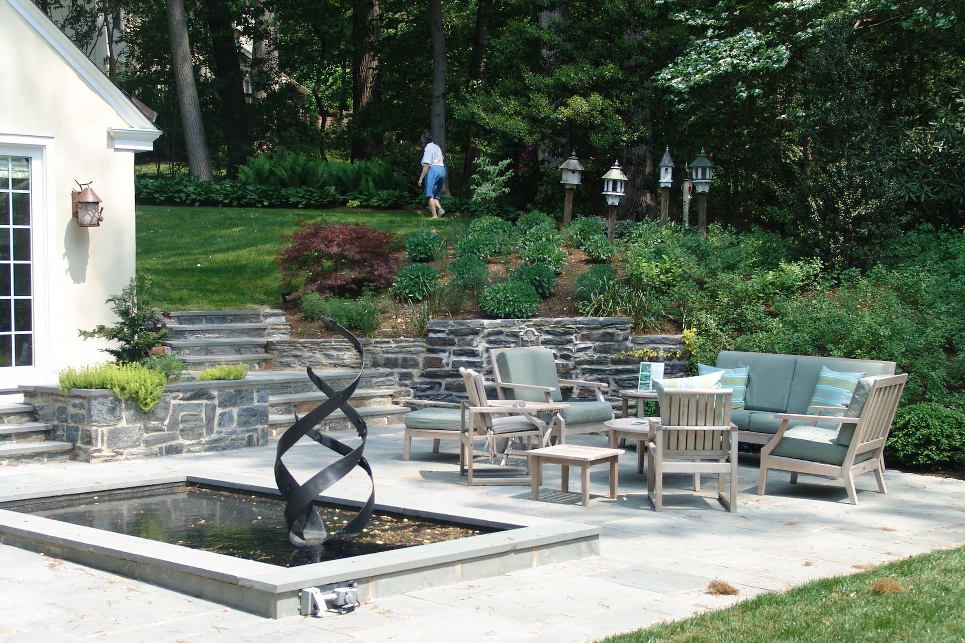 Estate garden with bluestone terrace, reflecting pool, and layered plantings by Fine Garden Creations